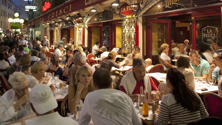 Diners eat at tables in the street outside restaurants Nice, France.