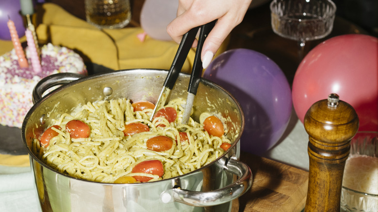 Someone using tongs to grab pasta out of a pot