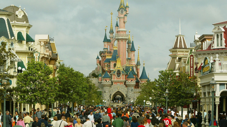 A crowd of tourists walk toward the Sleeping Beauty castle on Main Street at Disneyland Paris