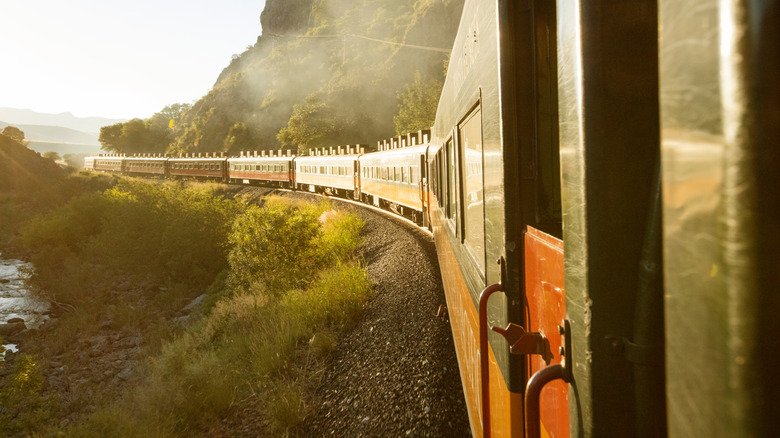 Famous red Chepe Express train traversing the landscape of Mexico's Copper Canyon at sunset
