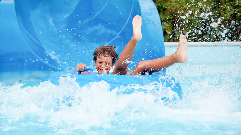 A smiling boy on an inflatable ring in the water, just after coming down a water slide