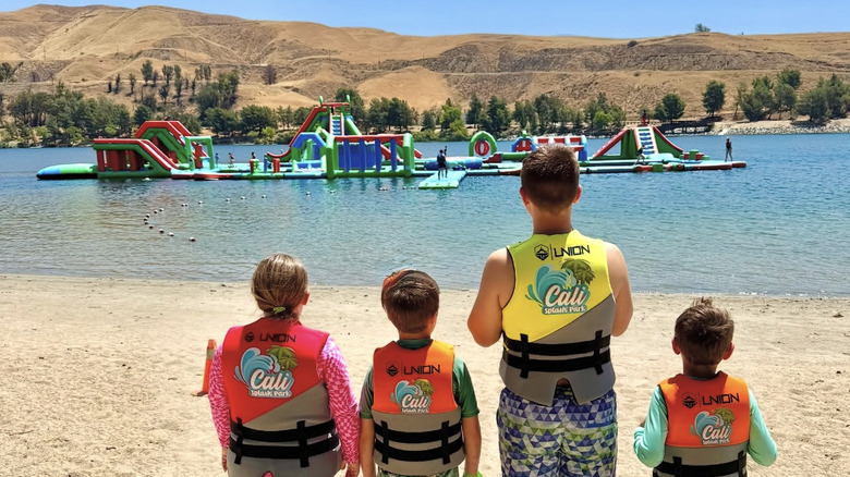A line of children look out onto Cali Splash Park, sitting on Castaic Lake