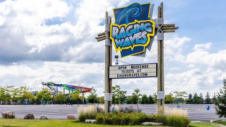 A sign for Raging Waves water park positioned in front of an empty parking lot