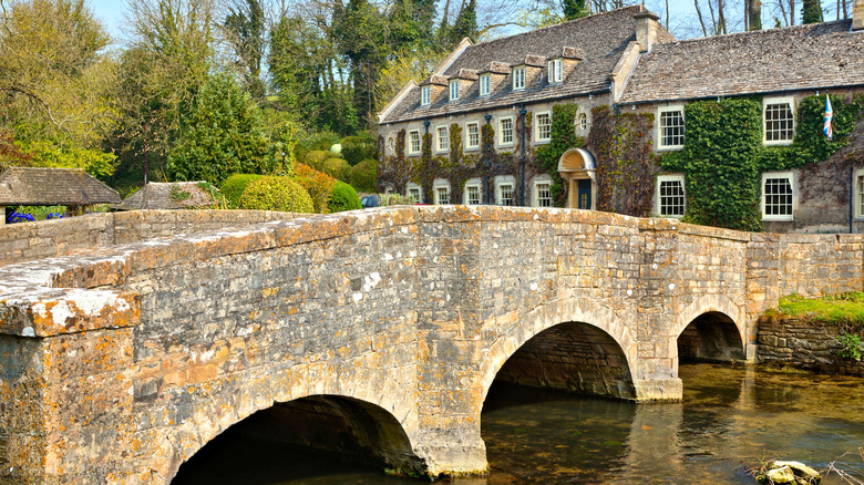 Bridge and quaint leafy buildings of the beautiful Cotswolds village of Bibury.