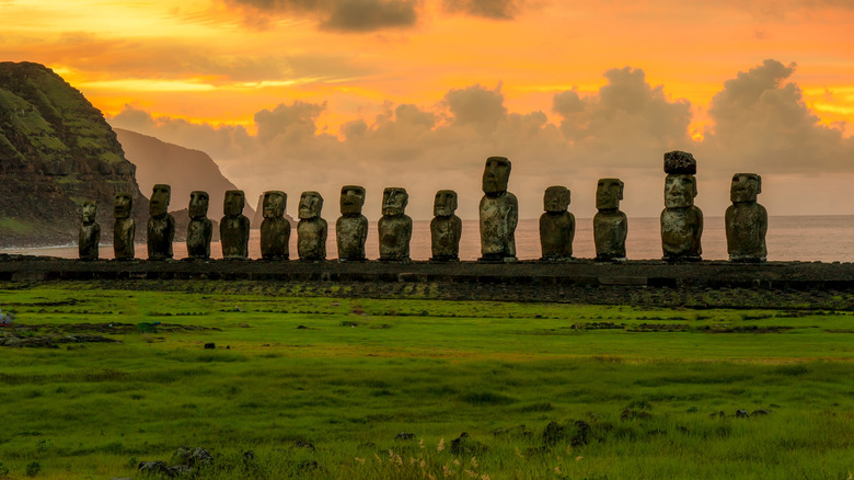 Line of moai statues along the shoreline near a grassy field on Easter Island, Chile