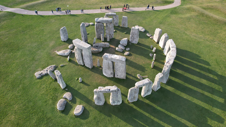 Aerial view over the giant stones of Stonehenge, England, with a trail nearby full of people