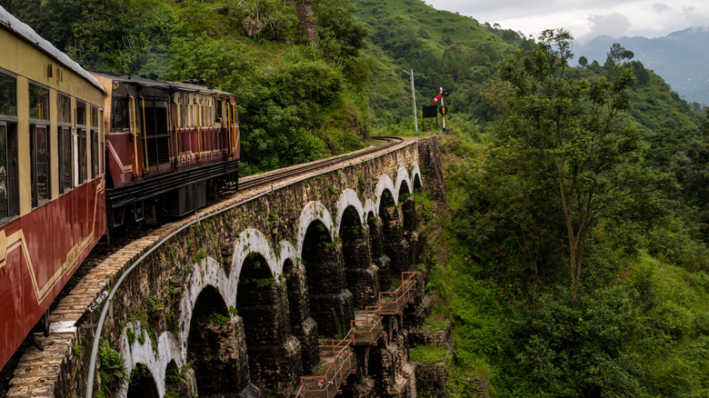 Red Himalayan Queen, the Kalka Shimla Toy Train, travels over a multilevel viaduct in the Indian mountains