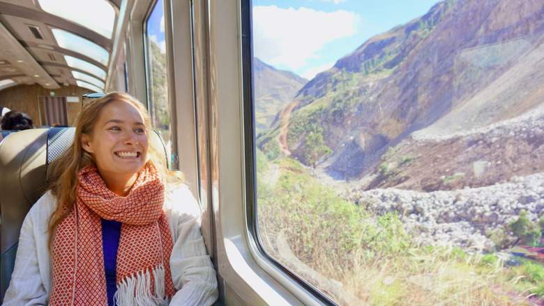 Tourist smiles as she looks out the panoramic windows on the Hiram Bingham Train traveling between Cusco and Aguas Calientes
