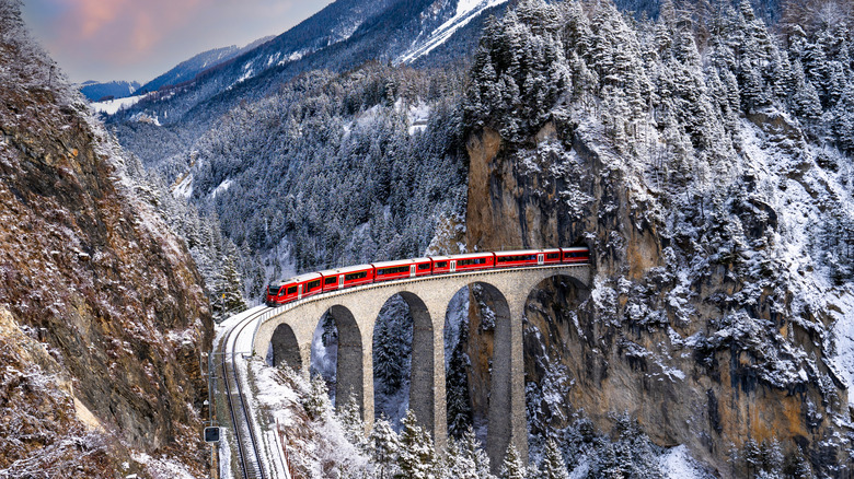 Aerial view of red train on viaduct in the snowy Swiss Alps