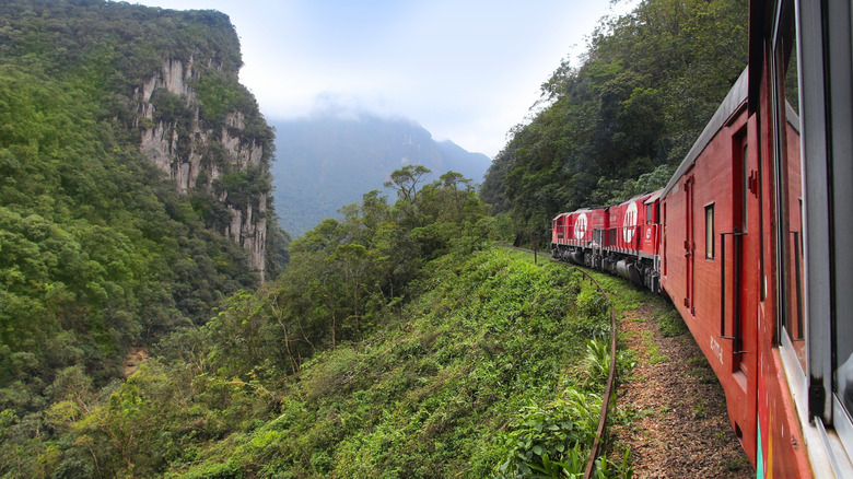 Red Serra Verde Express passing through high lush mountains in Brazil's Atlantic Forest