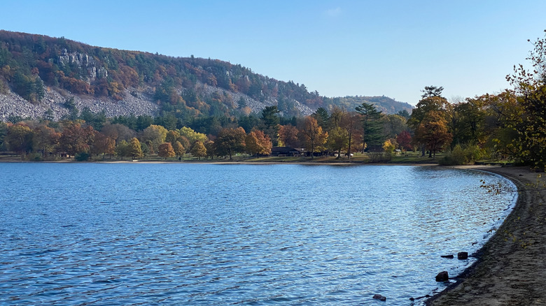 View of the bright blue glacial lake at Devil's Lake State Park in Wisconsin on a sunny fall day, with the trees starting to turn