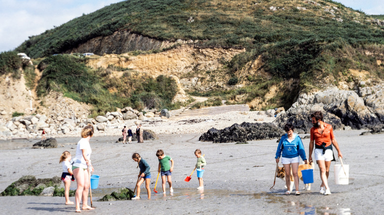 People on vacation at a beach in the early 1980s, with shovels and buckets