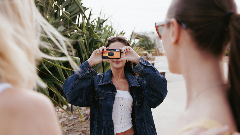 A person taking a picture of friends with a disposable camera