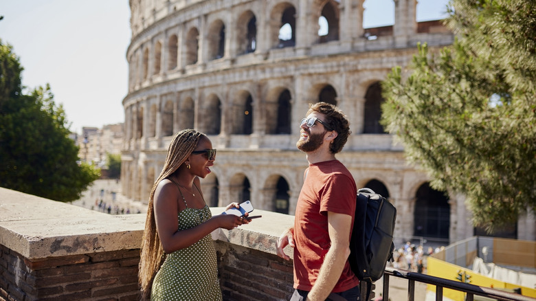 Two people chatting in front of the Colosseum in Rome, Italy