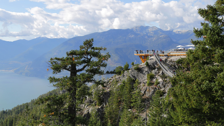 A suspension bridge leading to a lodge overlooking mountains and the sea