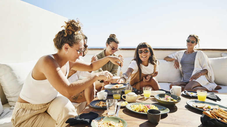 Group of travelers eating breakfast on a sunny terrace
