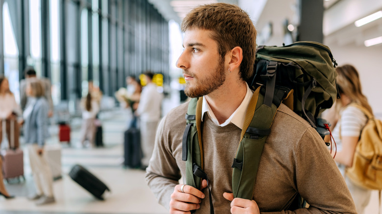 A man with a backpack on his back, standing inside an airport