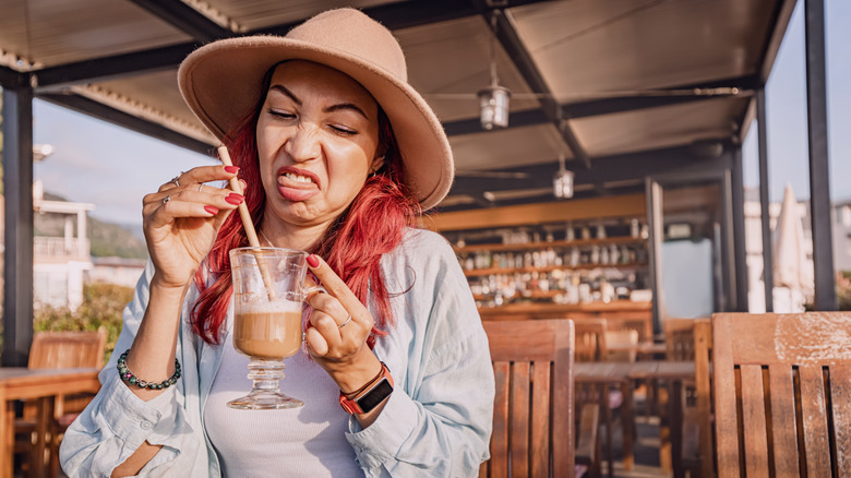 A woman makes a bad face while drinking coffee