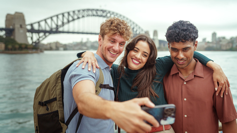 Three cheerful friends taking selfie with Sydney Harbour Bridge at the background
