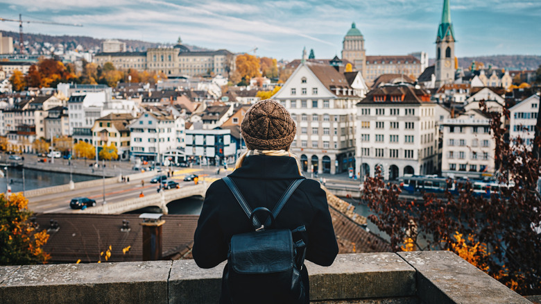 A blonde tourist looks out at the skyline of Zurich, Switzerland