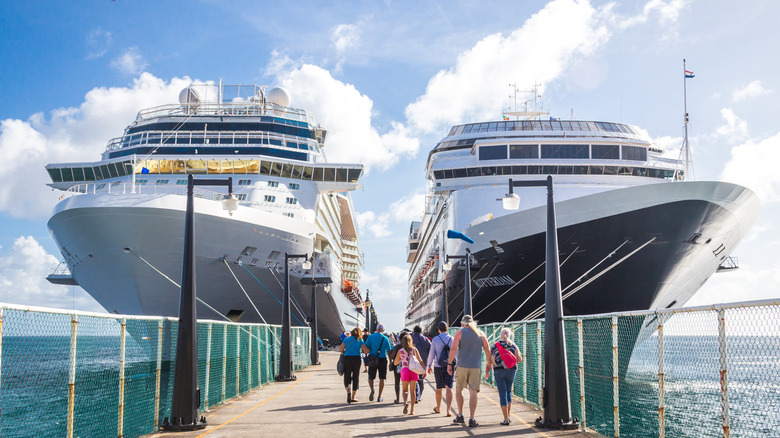 People walking towards two docked cruise ships, getting ready to board