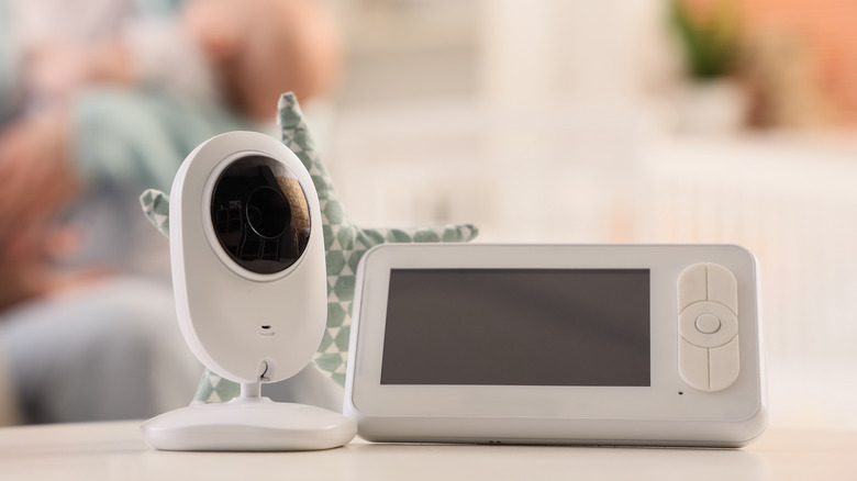A white baby monitor and camera on a desk with a blurred background