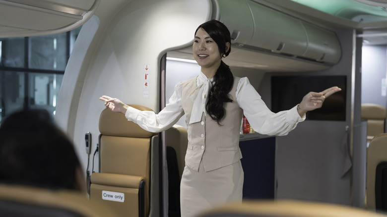 A flight attendant giving a safety briefing on a plane