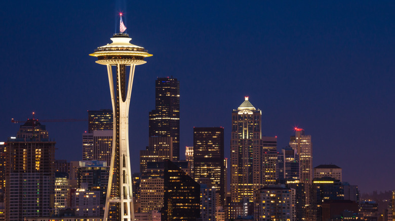 Seattle's Space Needle, topped with an American flag, lit up against the skyline at night