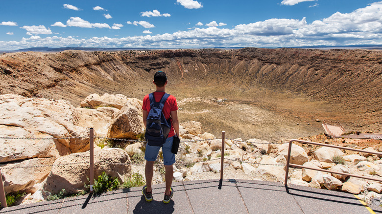a person is overlooking a massive crater on a sunny day