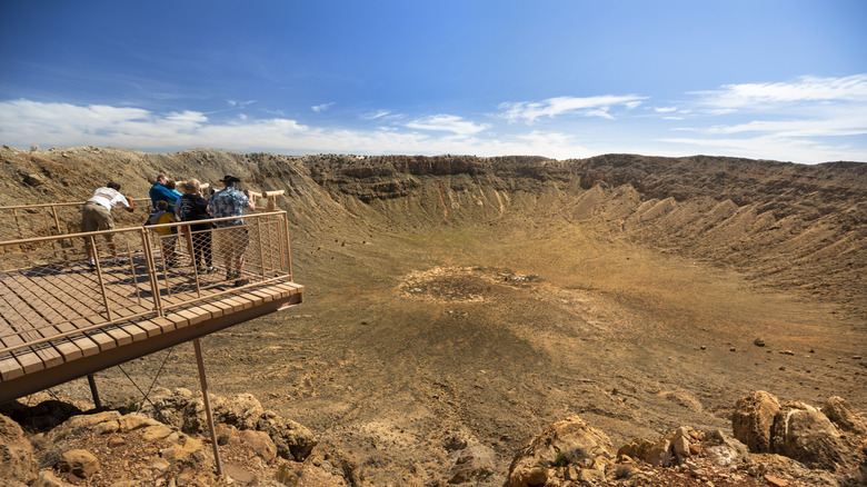 people standing on an overlook above the meteor crater