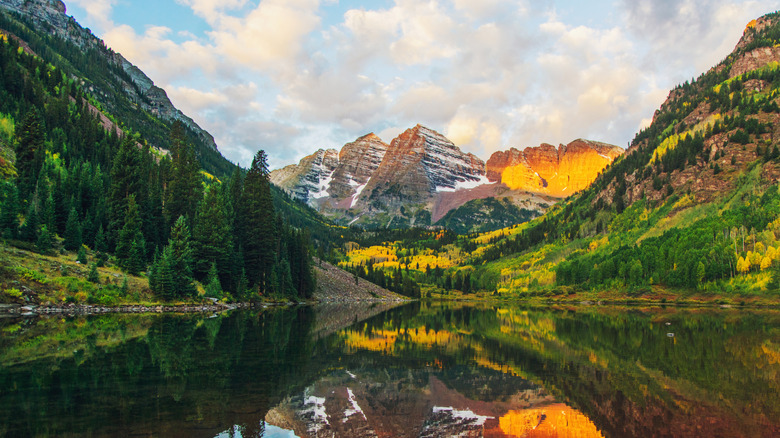 panoramic view of the maroon bell mountains with lake in foreground