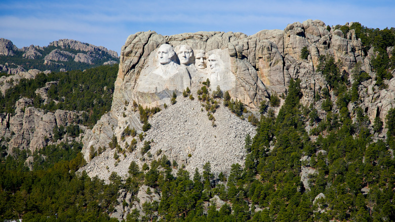 Aerial view of Mount Rushmore surrounded by the rocky cliffs and green forests of the Black Hills in South Dakota