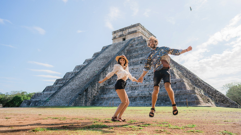 Couple jumping in front of the main temple at Chichen Itza, Mexico