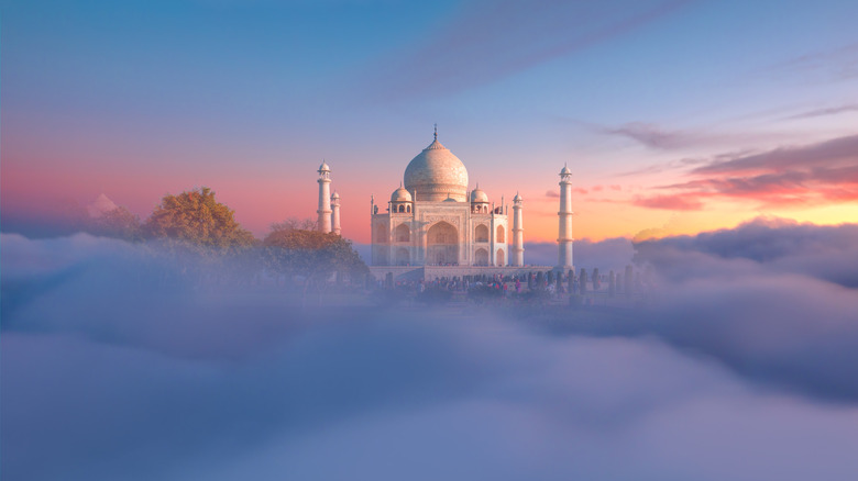 White Taj Mahal in India rising from the fog at sunrise