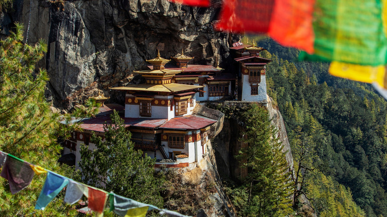 The Tiger's Nest framed by prayer flags perched along a mountain in Bhutan