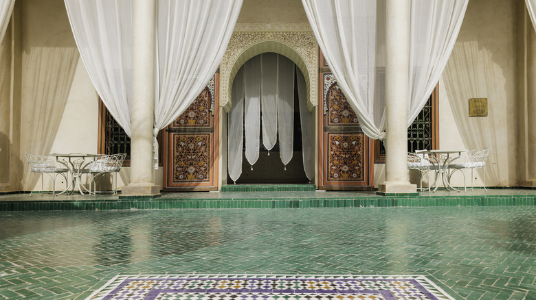Ornate tiled pooled in a Moroccan courtyard with arched doorway and columns, Marrakesh