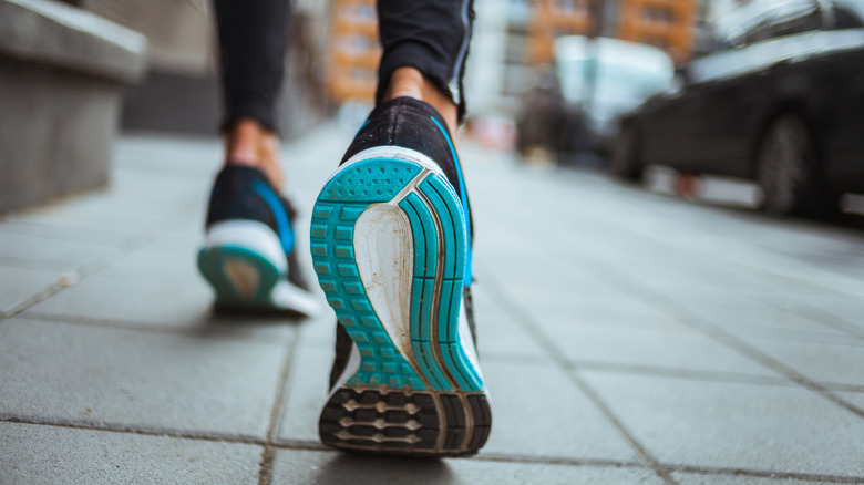 Close up shot of blue and white soles of runner's shoes on a city street