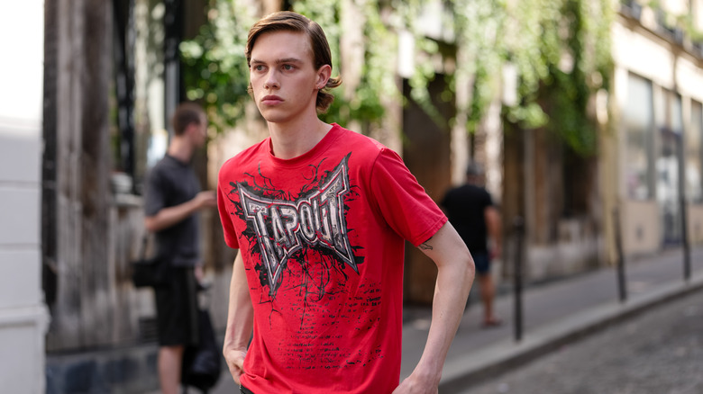 A model wears bright cherry red graphic pattern/print Tap Out MMA shirt in Paris