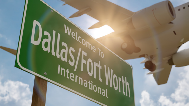 Airplane flying above Dallas–Fort Worth International Airport green road sign