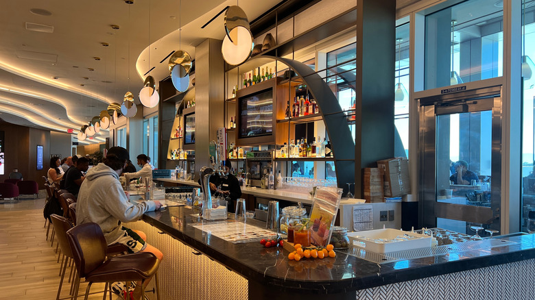 Travelers enjoying drinks at the indoor bar the LAX Delta Sky Club