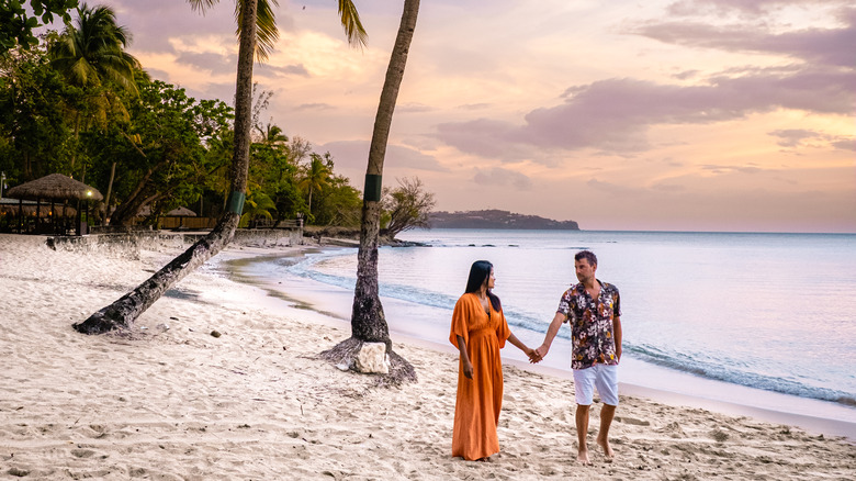 Couple holding hands on the beach at sunset in Saint Lucia.