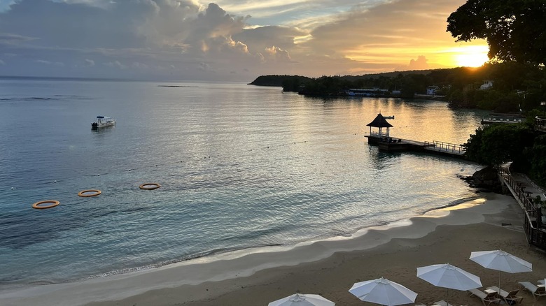 Beach loungers, ocean, and gazebo at sunset at Sandals Royal Plantation