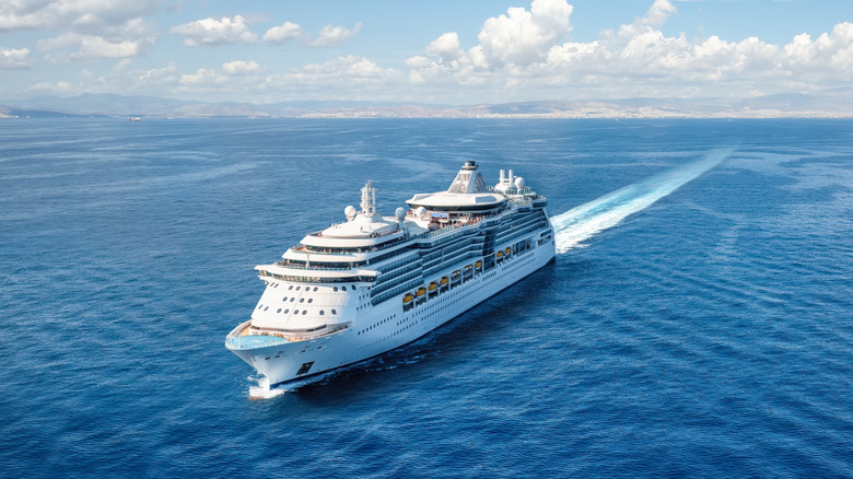 A large cruise ship sails over calm open ocean.