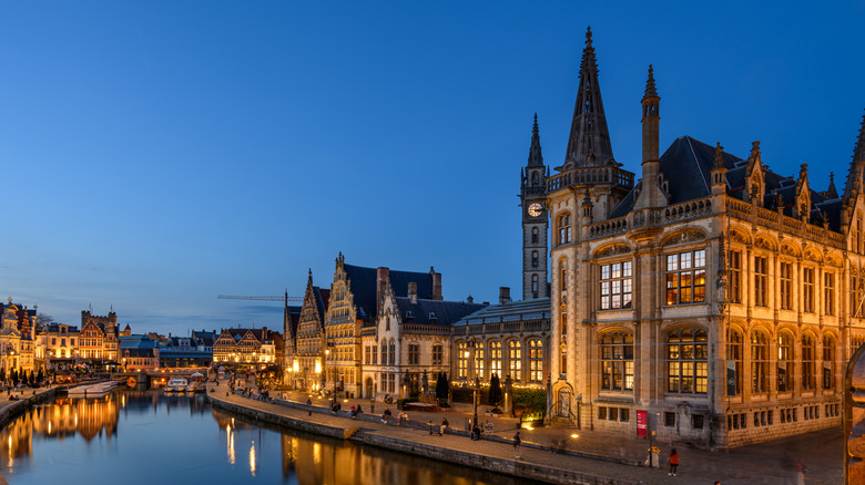 The gothic facades of buildings lit up at night on the riverside of Ghent, Belgium