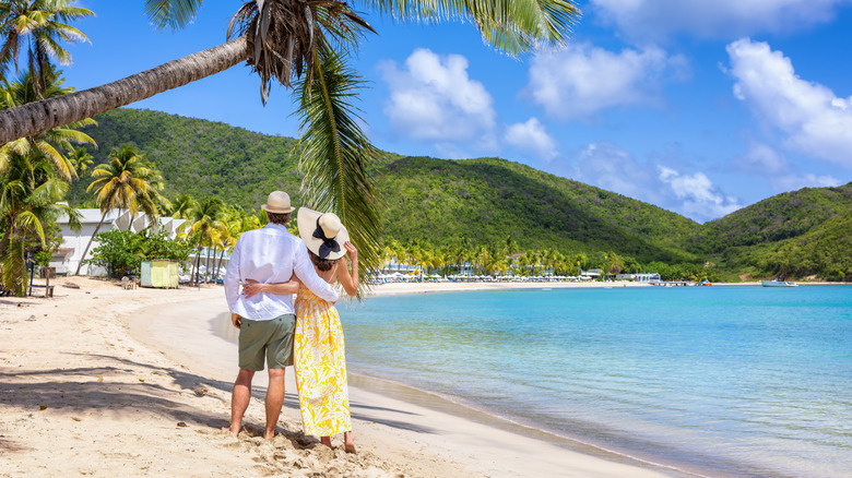 Couple embracing under palm trees on a picturesque beach, Antigua, Caribbean