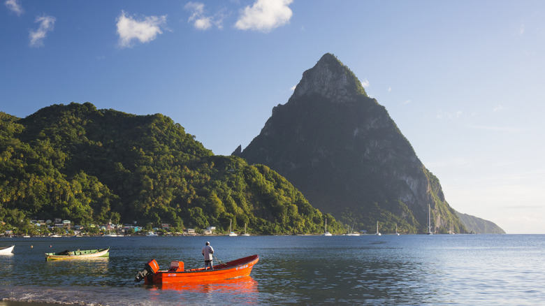An orange boat floating in the water among towering cliffs