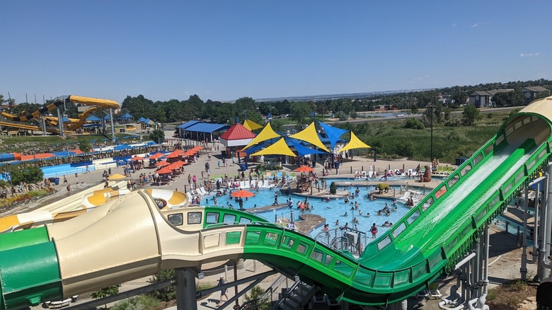 A green water slide, with a pool area in the background, at Water World in Colorado