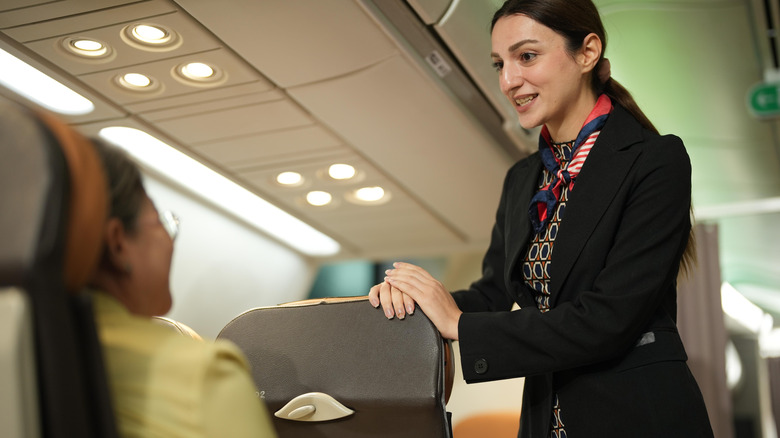 Flight attendant talking to a passenger on a plane