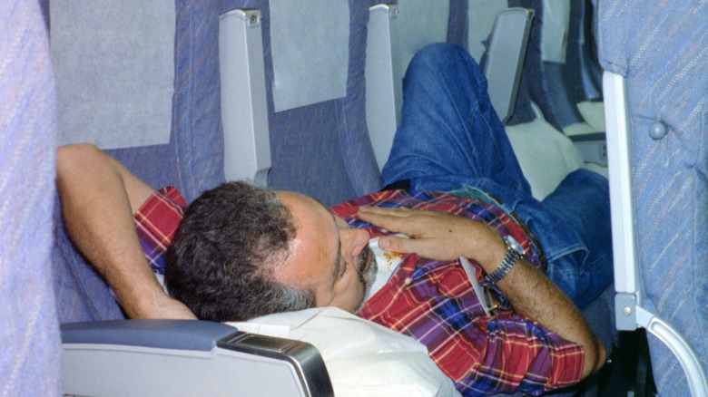 Person sleeping across an empty row on a flight