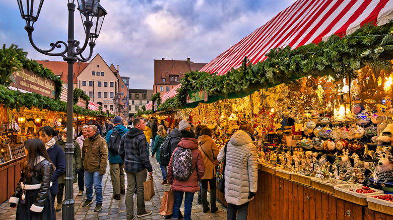 Pedestrians between the red and white roofed market stalls at the Christmas market in Nuremberg.